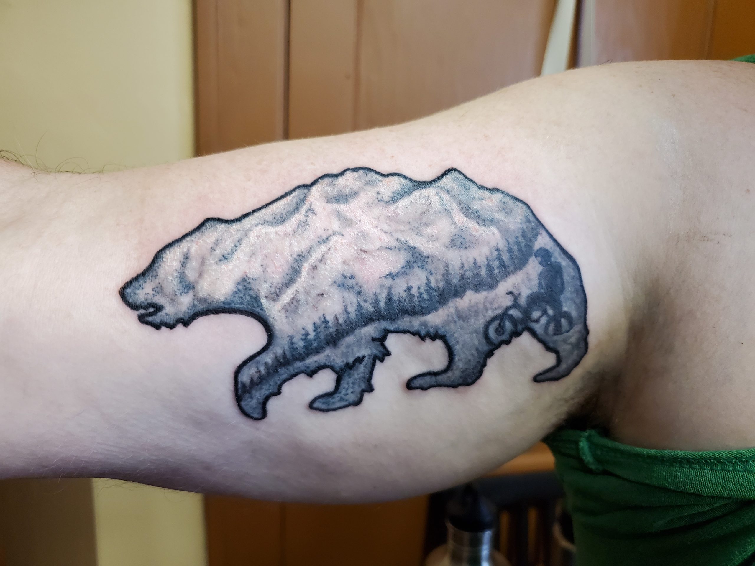 tattoo of bear image with black and gray style mountains and trees